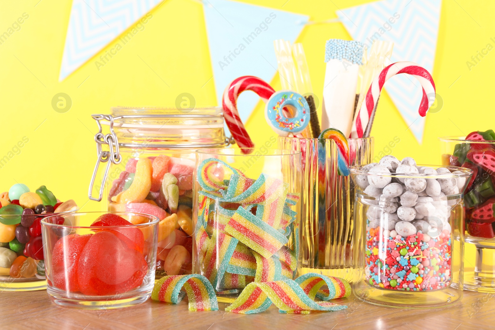 Photo of Candy bar. Many different sweets on wooden table against yellow background, closeup