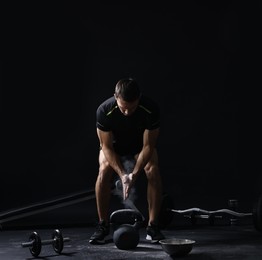 Man clapping hands with talcum powder before training with kettlebell on black background