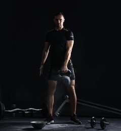 Photo of Man training with kettlebell on black background