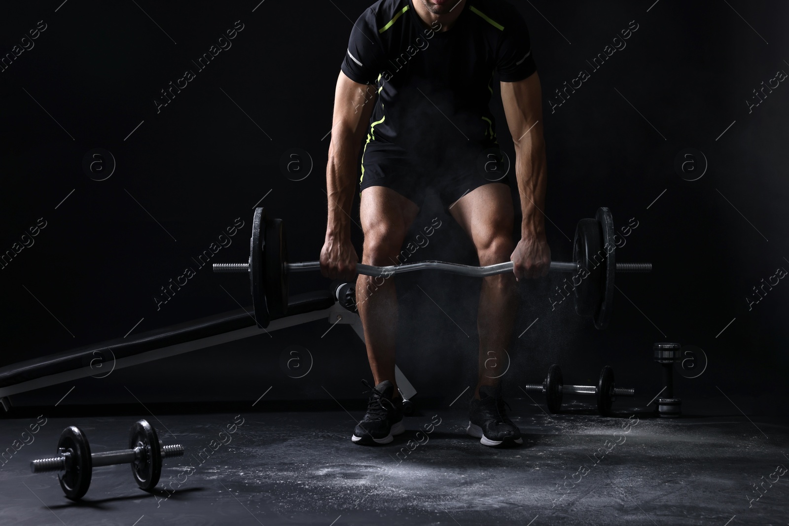 Photo of Man training with barbell on black background, closeup