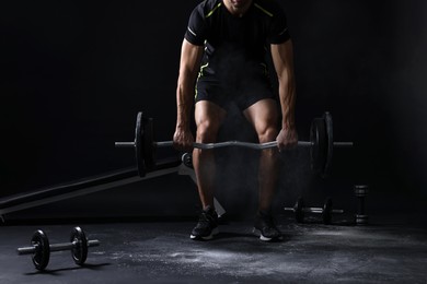 Photo of Man training with barbell on black background, closeup