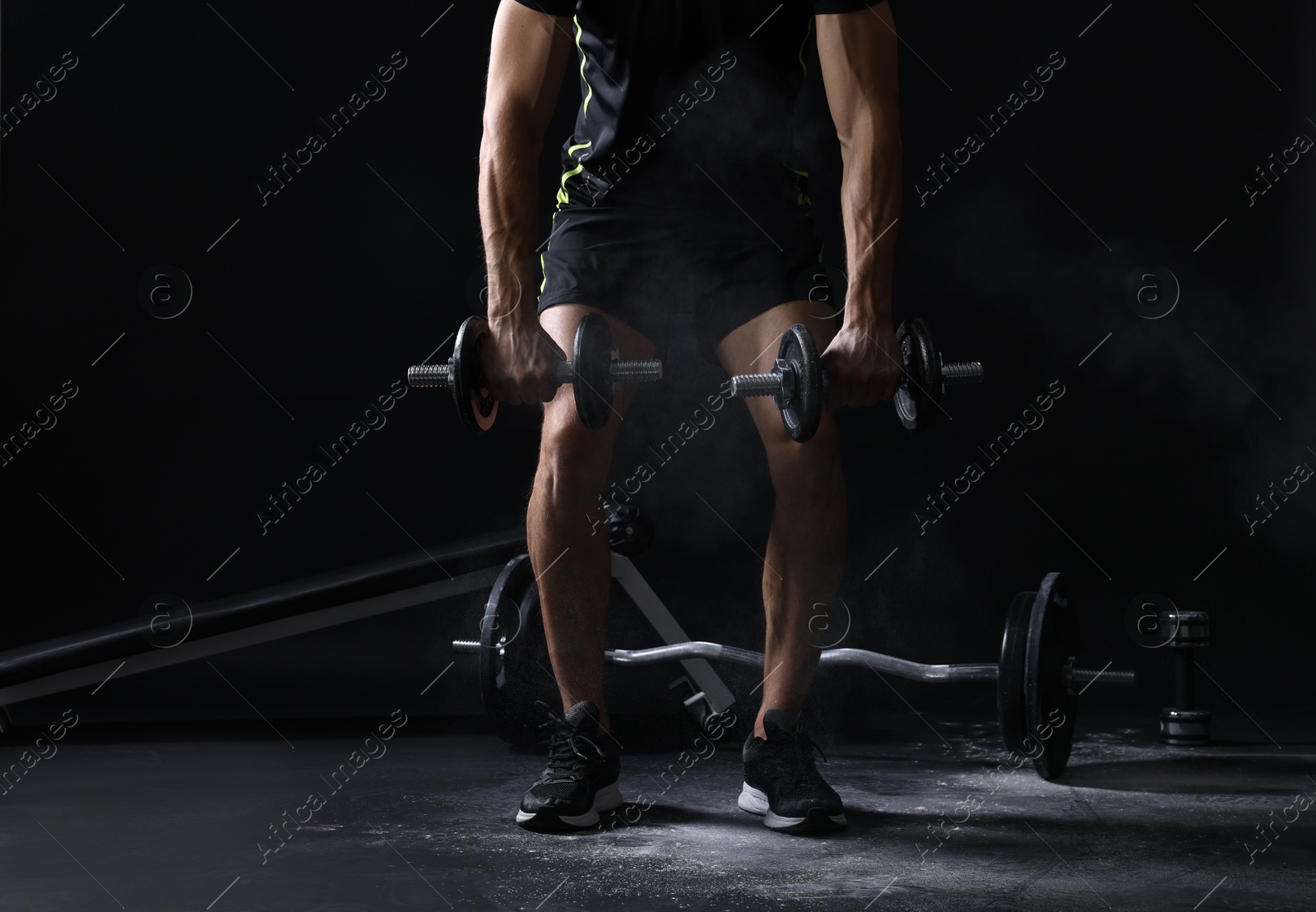 Photo of Man training with barbells against black background, closeup