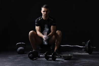 Photo of Man clapping hands with talcum powder before training on black background