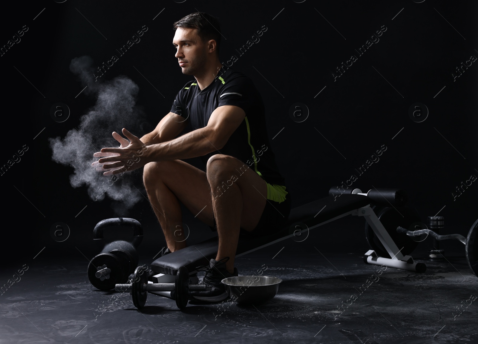 Photo of Man clapping hands with talcum powder before training on black background