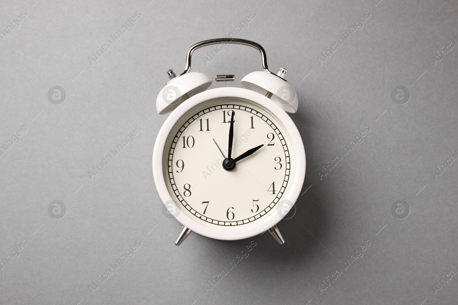 Photo of One white alarm clock on light grey background, top view