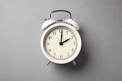 Photo of One white alarm clock on light grey background, top view