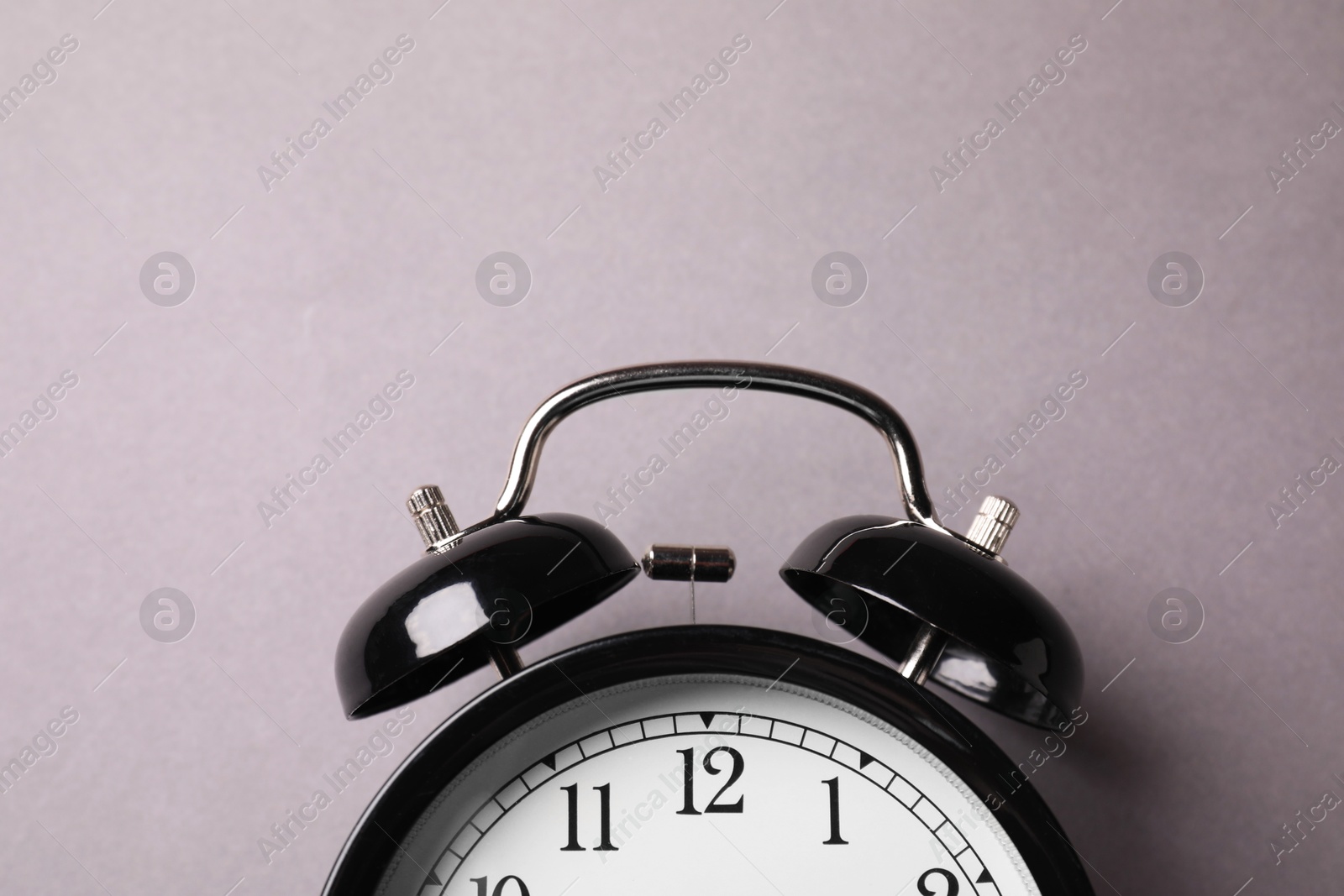 Photo of Black alarm clock on grey background, top view