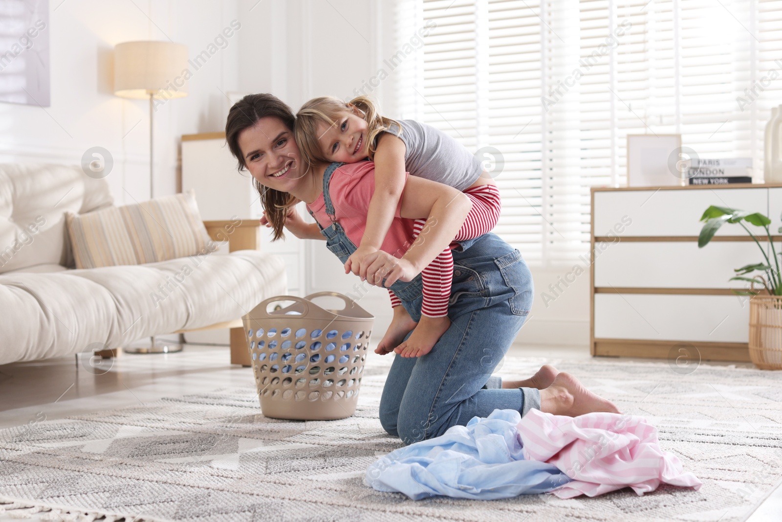 Photo of Little helper. Daughter and mother having fun while doing laundry at home