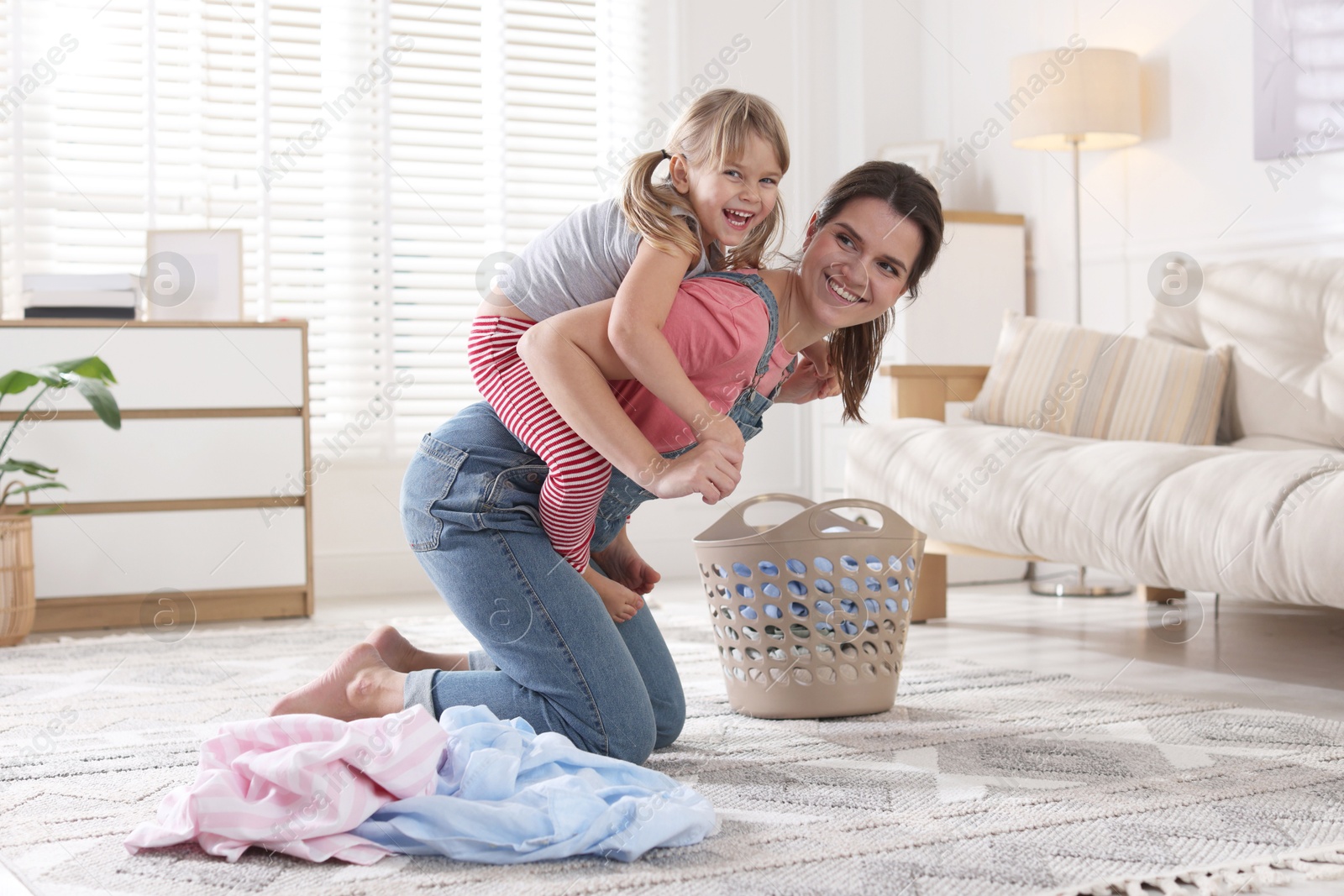 Photo of Little helper. Daughter and mother having fun while doing laundry at home