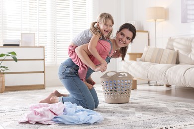 Little helper. Daughter and mother having fun while doing laundry at home