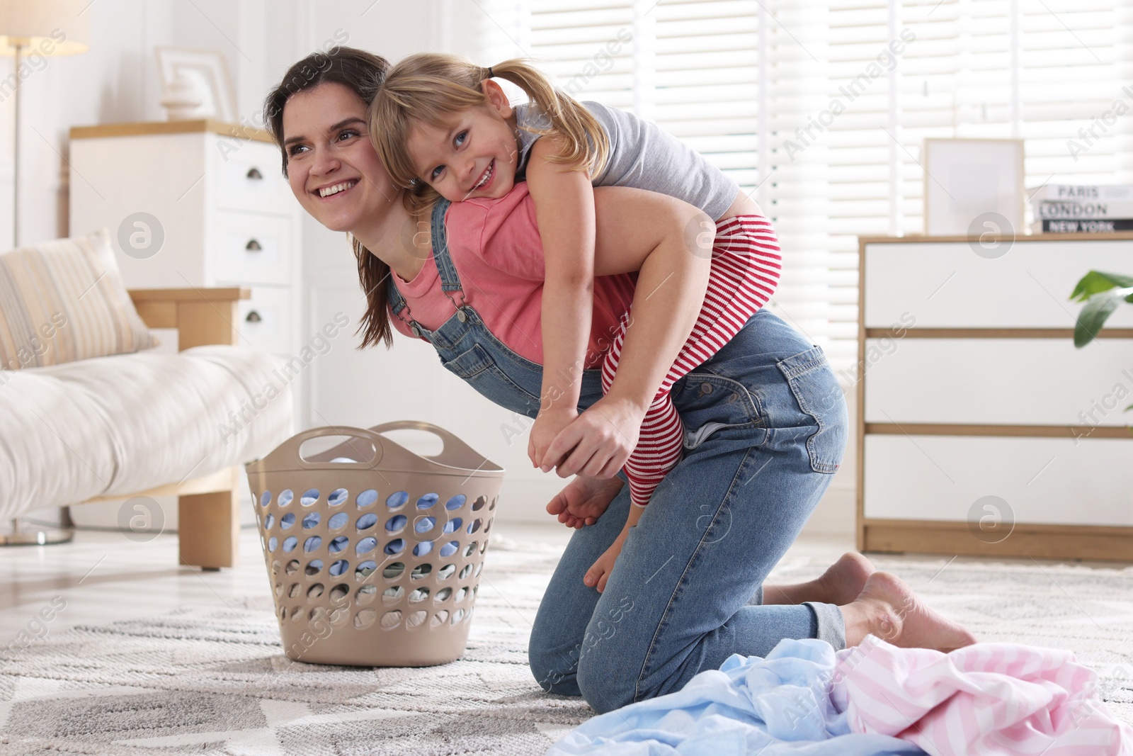 Photo of Little helper. Daughter and mother having fun while doing laundry at home