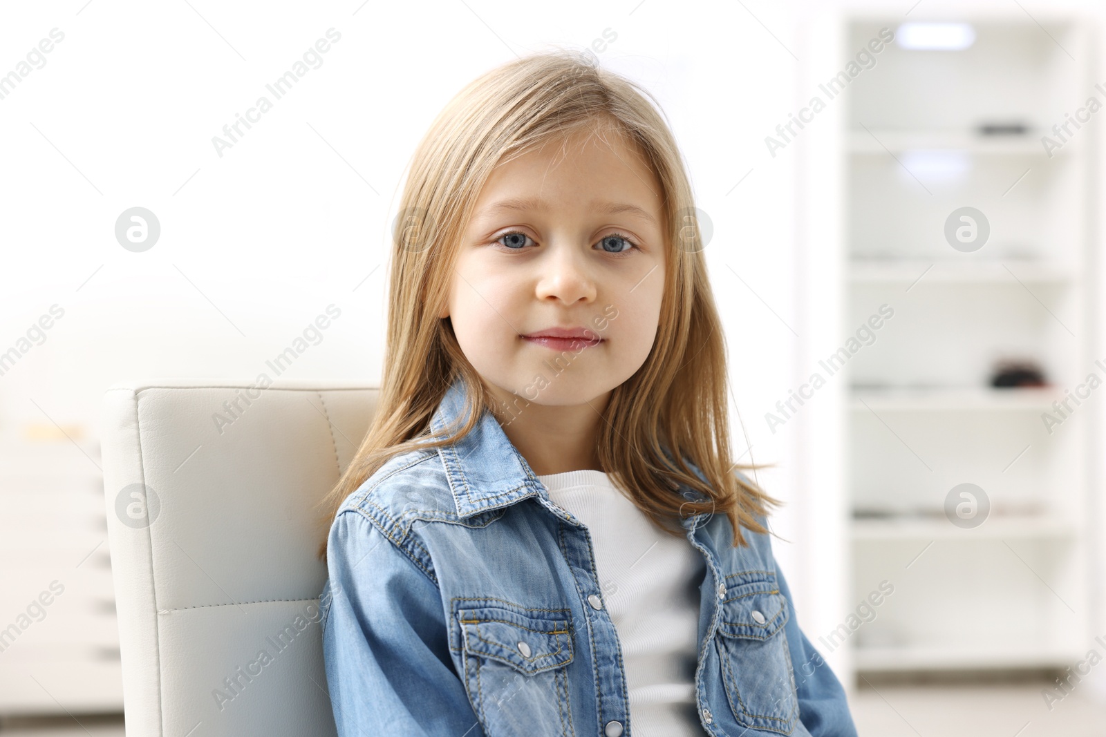 Photo of Portrait of cute little girl in denim jacket indoors