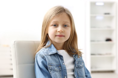 Photo of Portrait of cute little girl in denim jacket indoors