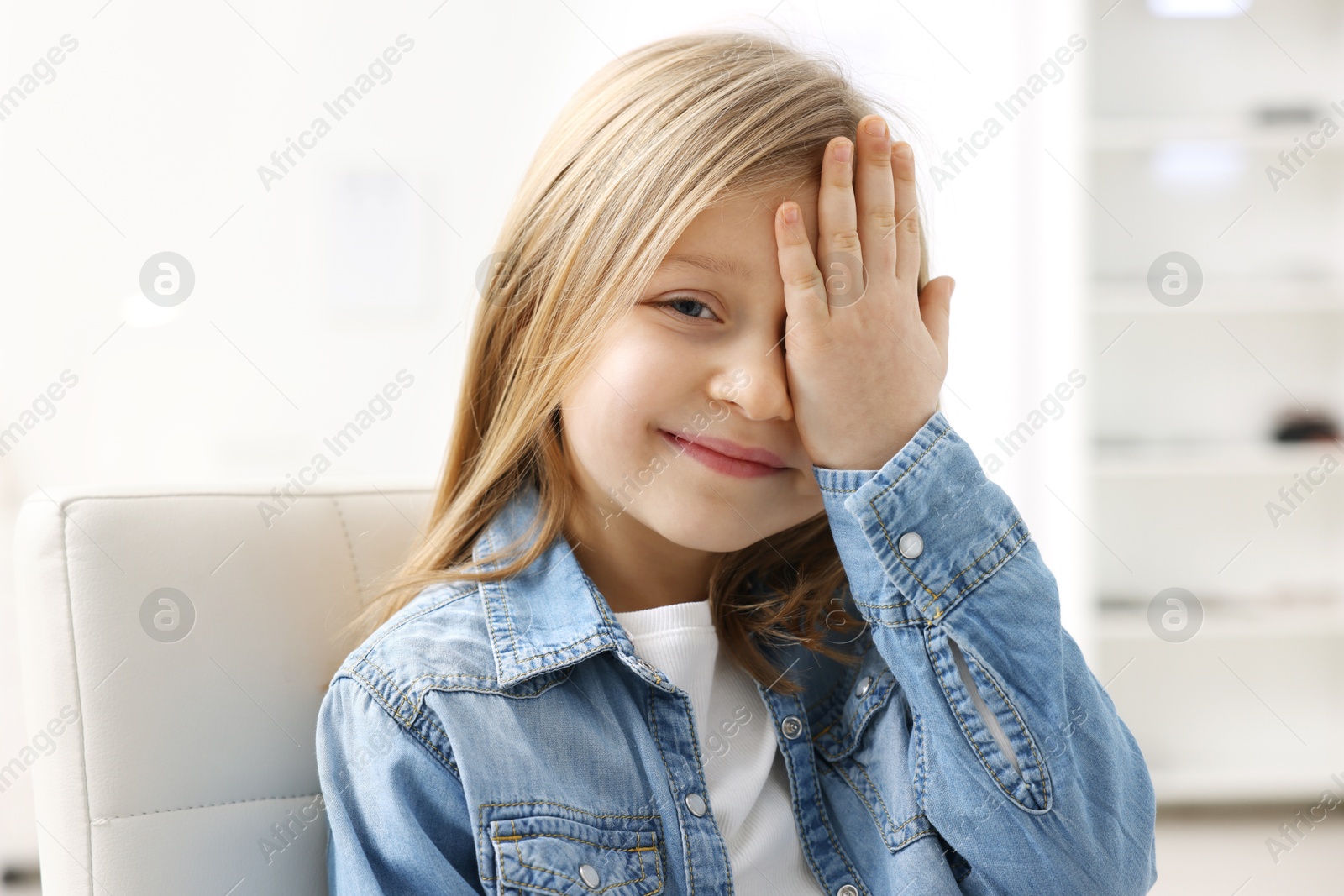 Photo of Little girl covering her eye at ophthalmologist office