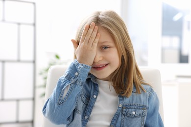 Photo of Little girl covering her eye at ophthalmologist office