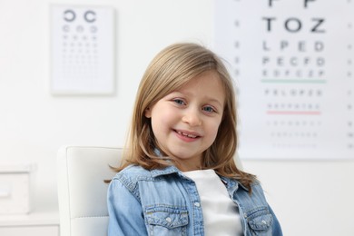 Photo of Portrait of cute little girl at ophthalmologist office. Eye examination