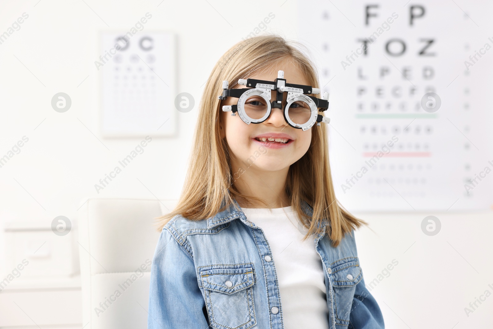 Photo of Vision testing. Little girl with trial frame at ophthalmologist office