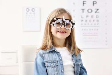 Photo of Vision testing. Little girl with trial frame at ophthalmologist office