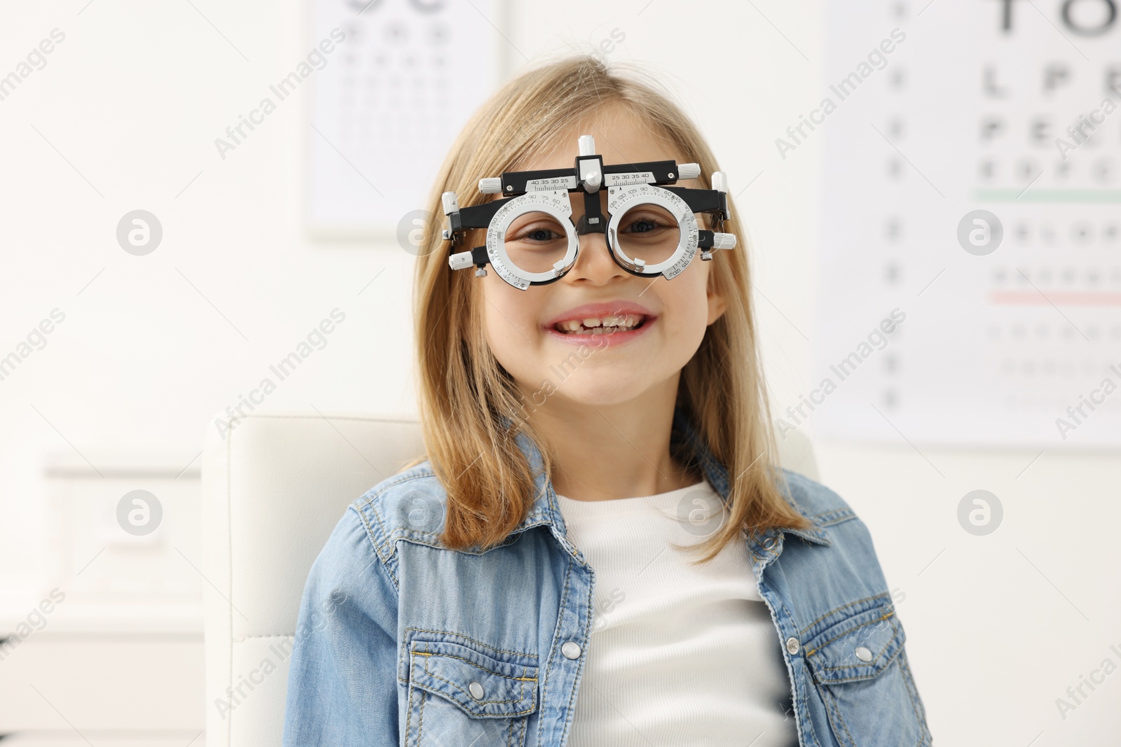 Photo of Vision testing. Little girl with trial frame at ophthalmologist office