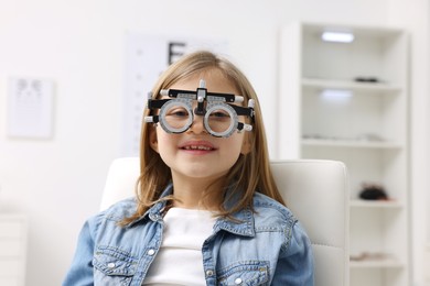 Photo of Vision testing. Little girl with trial frame at ophthalmologist office