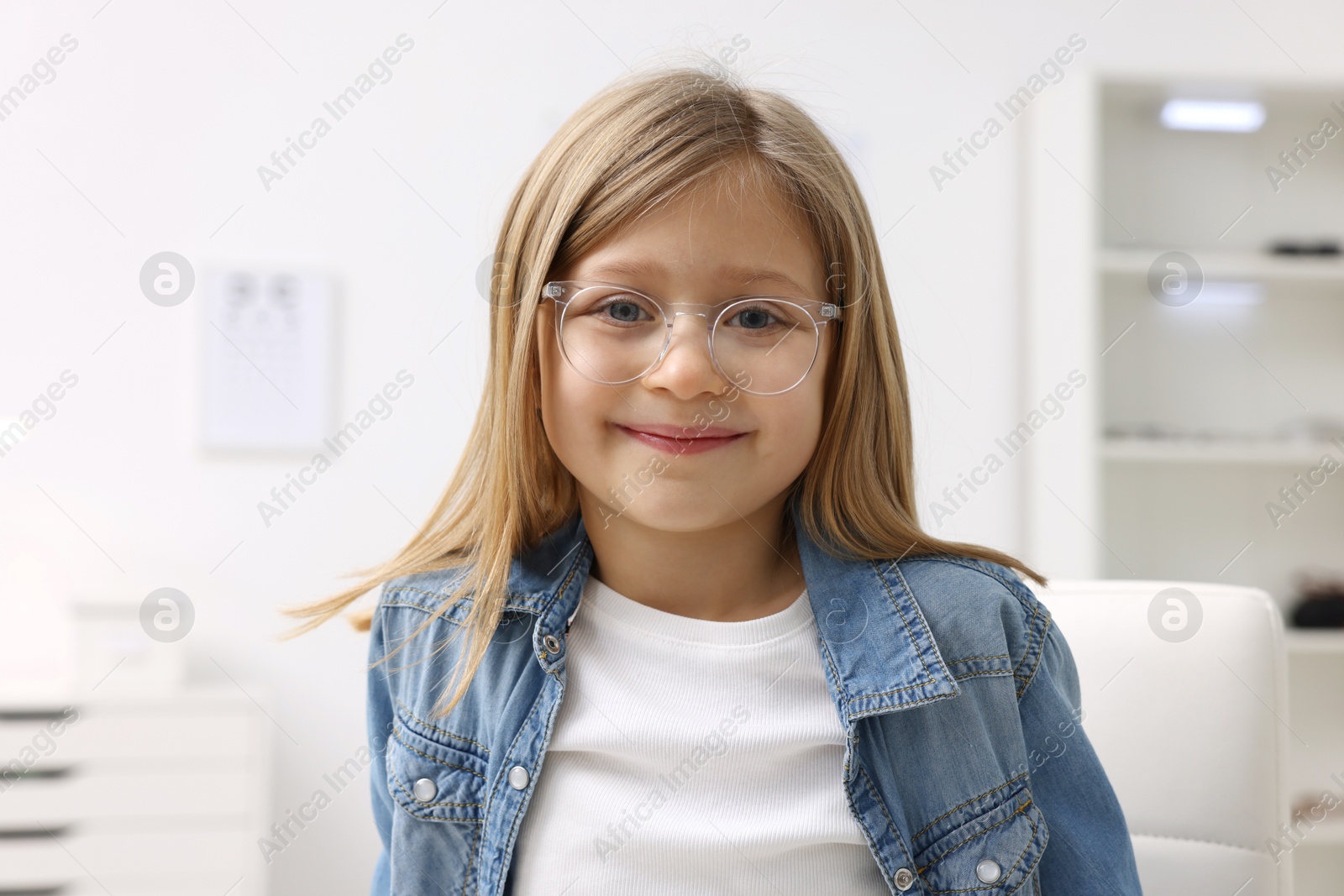 Photo of Little girl trying glasses at ophthalmologist office