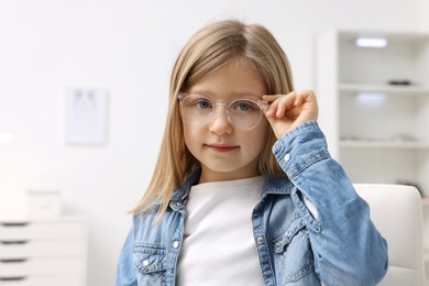 Photo of Little girl trying glasses at ophthalmologist office