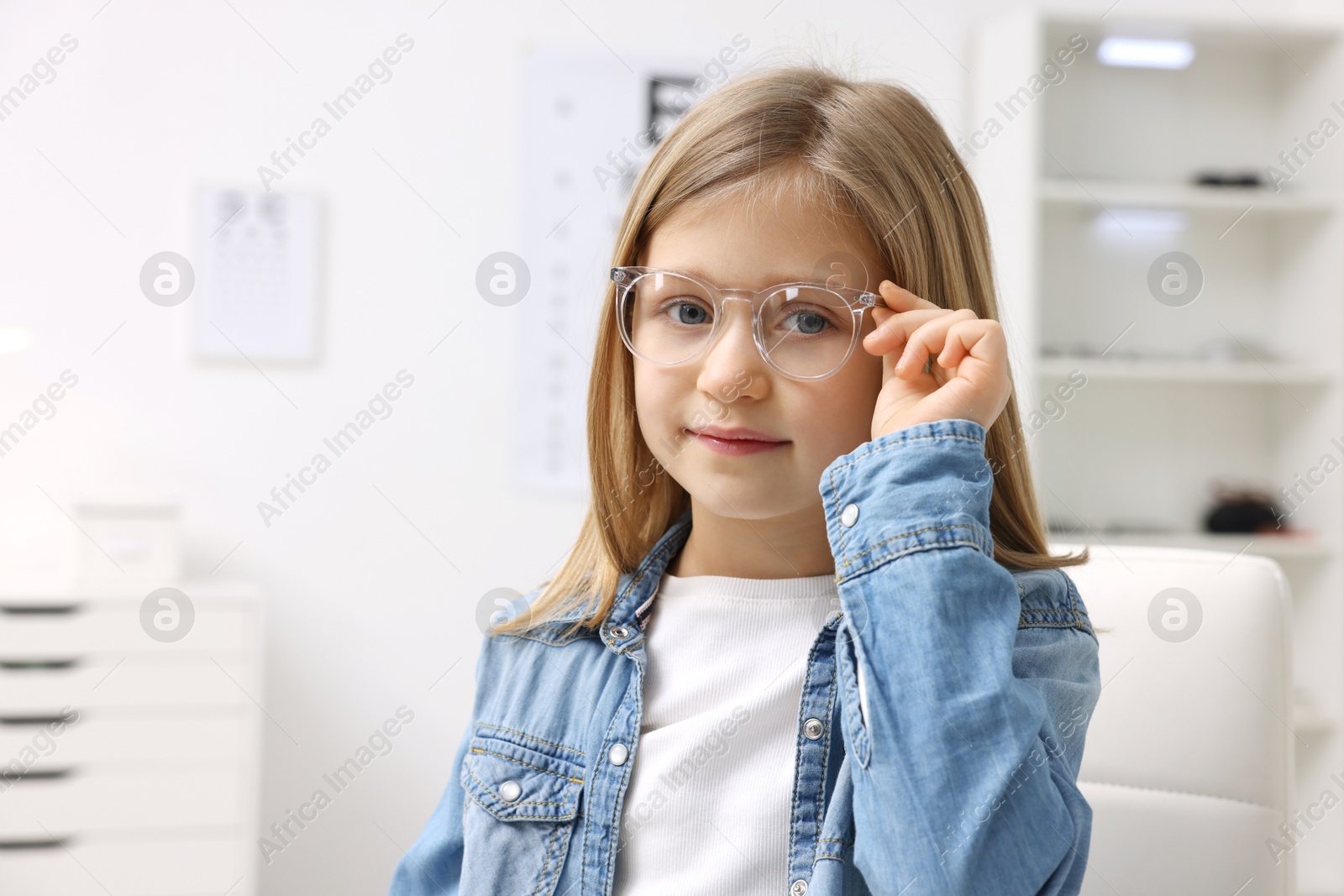 Photo of Little girl trying glasses at ophthalmologist office