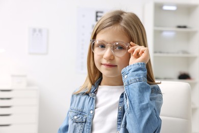 Photo of Little girl trying glasses at ophthalmologist office