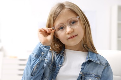 Photo of Little girl trying glasses at ophthalmologist office