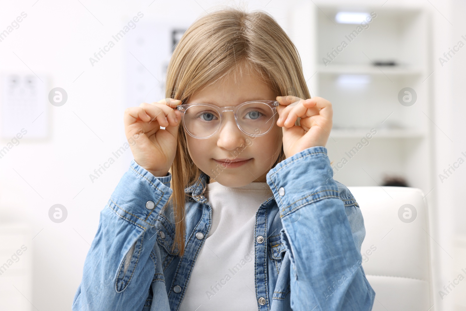 Photo of Little girl trying glasses at ophthalmologist office