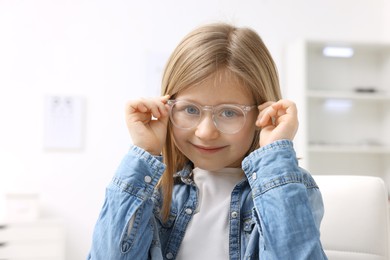 Photo of Little girl trying glasses at ophthalmologist office