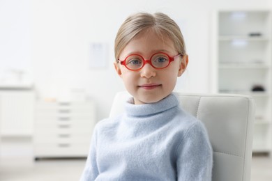 Photo of Little girl trying glasses at ophthalmologist office