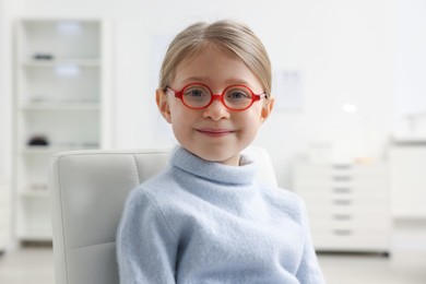 Photo of Little girl trying glasses at ophthalmologist office