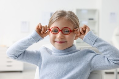 Photo of Little girl trying glasses at ophthalmologist office