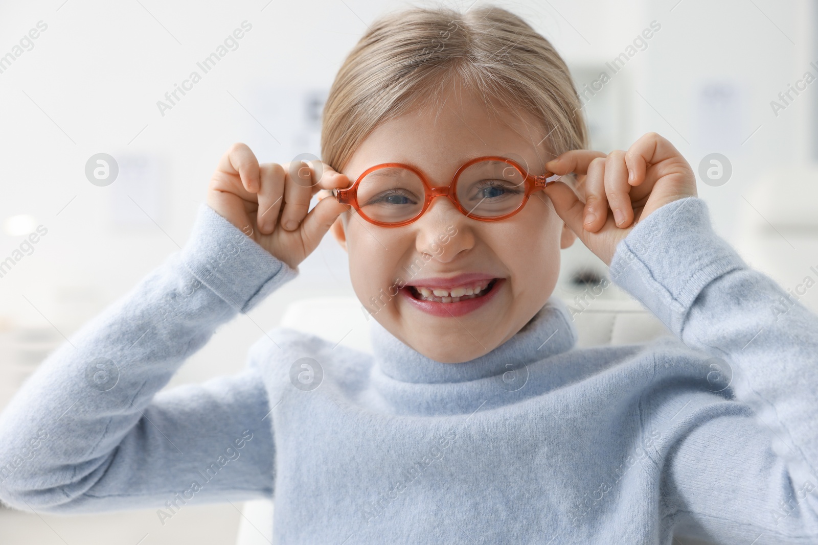 Photo of Little girl trying glasses at ophthalmologist office