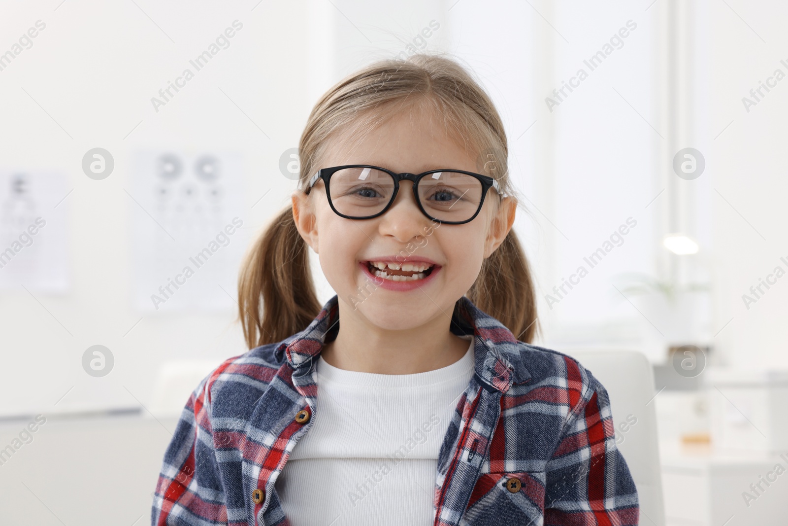 Photo of Little girl trying glasses at ophthalmologist office