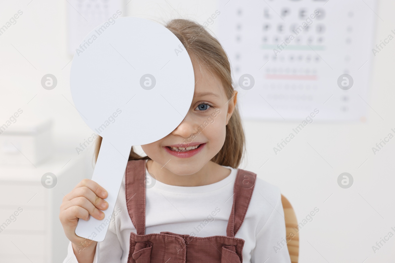 Photo of Little girl covering her eye at ophthalmologist office