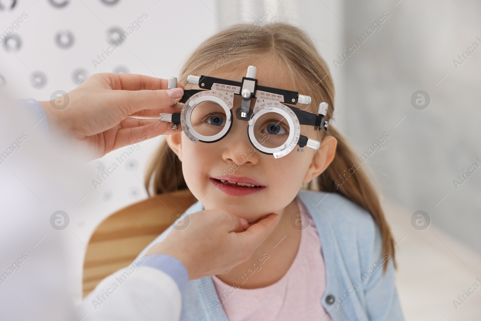 Photo of Ophthalmologist examining patient's vision with trial frame indoors, closeup