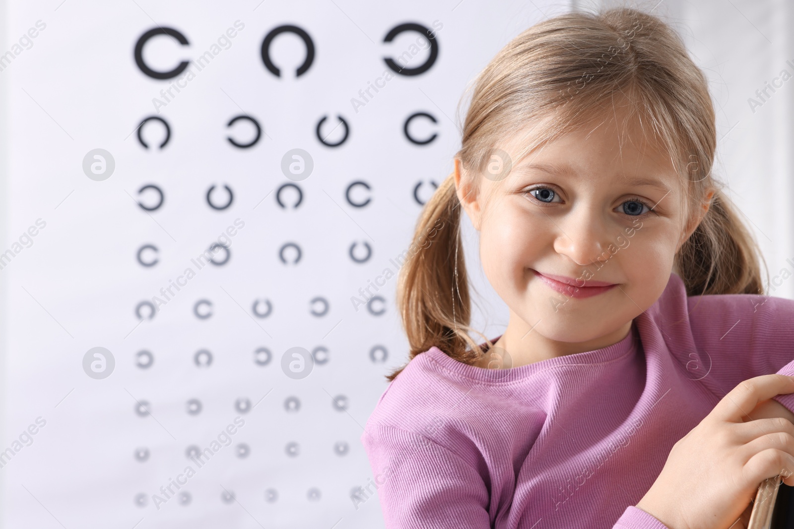 Photo of Little girl against vision test chart. Eye examination