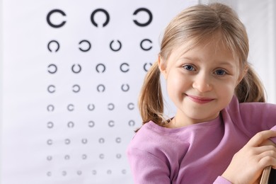 Photo of Little girl against vision test chart. Eye examination