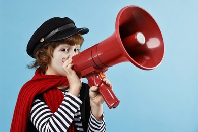 Photo of Cute boy in mime costume with megaphone on light blue background. Surprise party