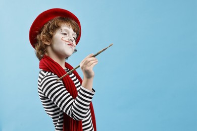 Photo of Cute boy in mime costume with brush on light blue background, space for text. Surprise party