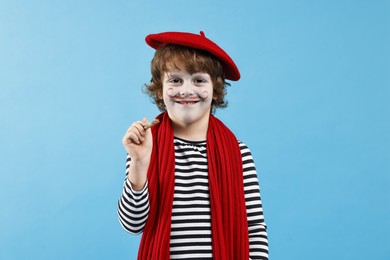 Photo of Smiling boy in mime costume with brush on light blue background. Surprise party