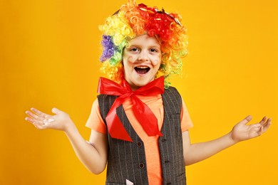 Photo of Happy little boy dressed like clown on orange background. Surprise party