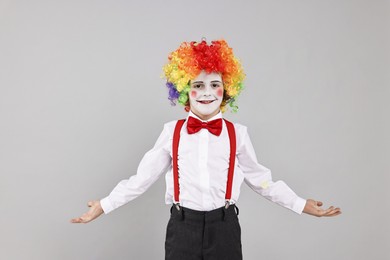 Happy little boy dressed like clown on grey background. Surprise party