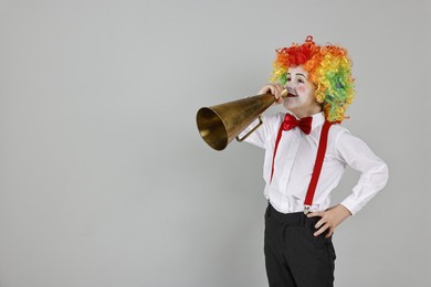 Photo of Little boy dressed like clown with megaphone on grey background, space for text. Surprise party