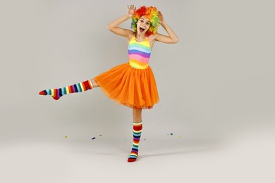 Photo of Happy girl dressed like clown on grey background. Surprise party