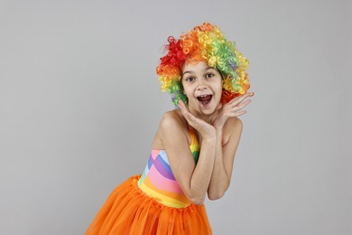 Photo of Happy girl dressed like clown on grey background. Surprise party