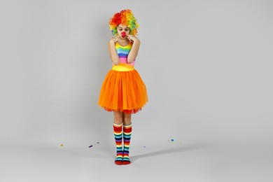 Photo of Cute girl dressed like clown on grey background. Surprise party