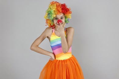 Photo of Cute girl dressed like clown on grey background. Surprise party